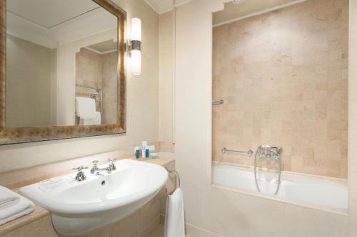 een badkamer met een wastafel, een bad en een spiegel bij Stendhal Hotel in Rome