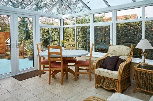 a conservatory with a table and chairs in a room with windows at Sunshine Corner in West Mersea