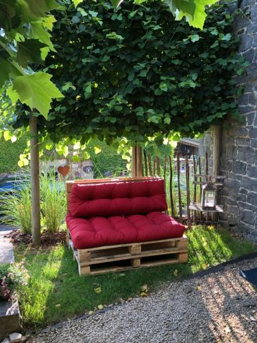 a red couch sitting under a tree in a yard at Gîte de Corbion une envie d'Ailleurs 6personnes et le Pt Bonheur 2 personnes in Leignon