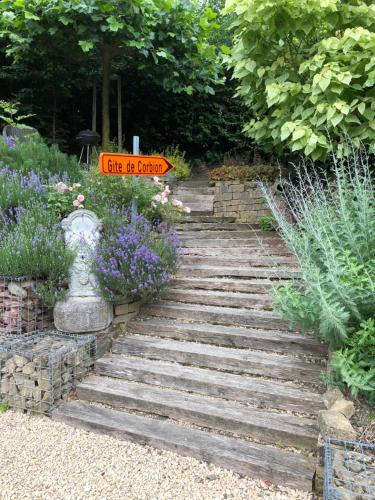 een tuin met een stenen pad met bloemen en een bord bij Gîte de Corbion in Leignon