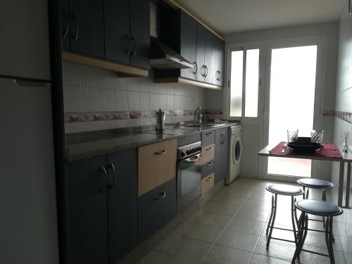 a kitchen with blue cabinets and two stools in it at Gonga House in Tarifa