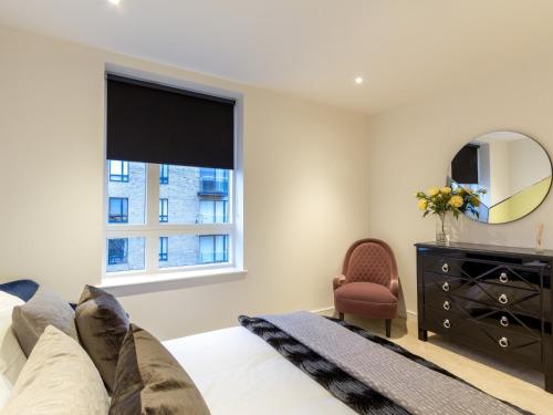 um quarto com uma cama, um espelho e uma cómoda em 2 Bed Property Close to Heathrow Airport em Hounslow