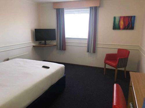 a bedroom with a bed, chair, desk and television at Days Inn Hotel Leicester in Leicester