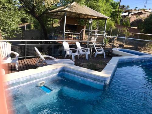 a swimming pool with chairs and a deck with a table at Terrazas del Diquecito in Villa Carlos Paz