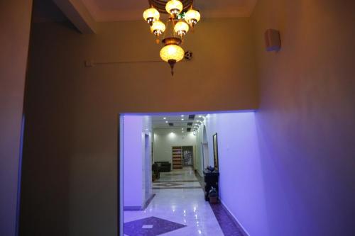 a hallway with a chandelier on the ceiling and a hallway with a stair at Ibra Plaza Hotel in Ibrā