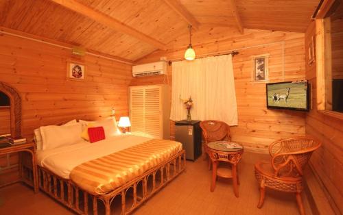 a bedroom with a bed in a log cabin at Alcove Resort Vagator in Vagator