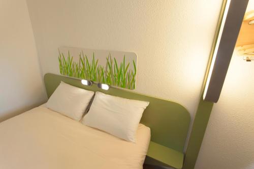 a bed with a green headboard with white pillows at ibis budget Cherbourg - La Glacerie in Cherbourg en Cotentin