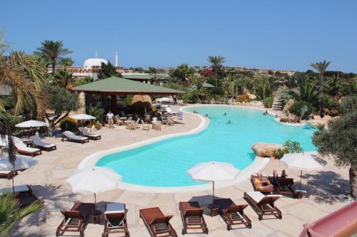 Cupola Bianca Resort في لامبيدوسا: مسبح في منتجع فيه كراسي ومظلات