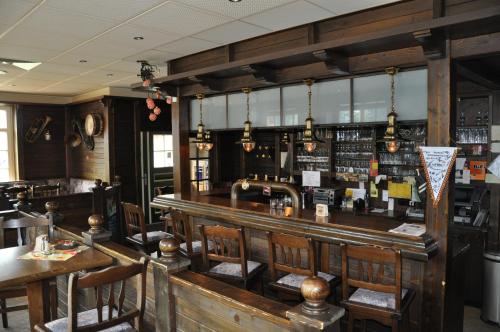 a bar in a restaurant with wooden tables and chairs at Schützenhof Ahlerstedt in Ahlerstedt