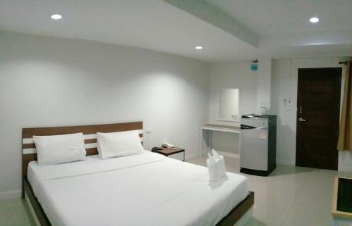 a bedroom with a large white bed and a refrigerator at DD Boutique Resort in Ban Wat Pa