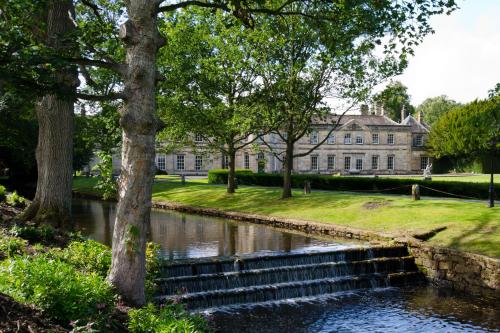 a house with a canal in front of a building at Grantley Hall in Ripon