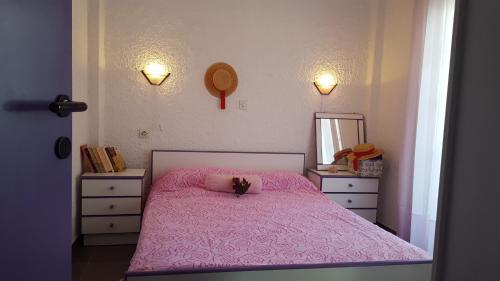 a bedroom with a pink bed and a mirror at Cozy summer house by the beach in Fourka