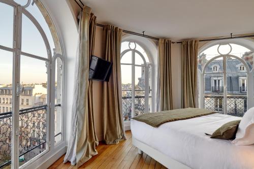 a bedroom with a bed and two large windows at Tinah Paris, Réaumur - Montorgeuil in Paris