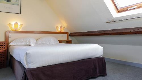 a bedroom with a bed with white sheets and a window at Les Bains de Mer Riviera Bretonne in Bénodet
