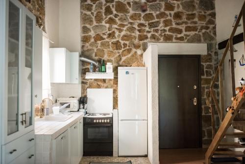 a kitchen with a white refrigerator and a stone wall at Stone Villas in Nea Roda