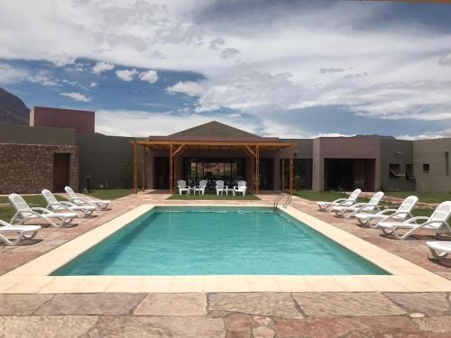 a swimming pool with chairs and a table and a house at Hotel Castillos de Cafayate in Cafayate
