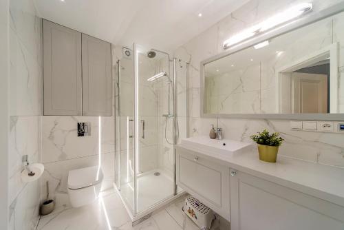 a white bathroom with a shower and a sink at Sea Apartment Leśne Tarasy in Dziwnówek
