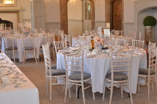 a room with tables and chairs with white tablecloths at Weston Hall in Stafford