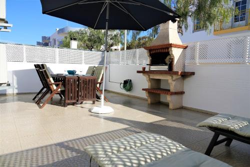 a patio with an umbrella and a table and a grill at Altura da Maré - Apartamento Duna in Altura