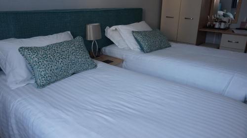 two beds in a hotel room with white sheets and pillows at Bluebird Lodge in Coniston