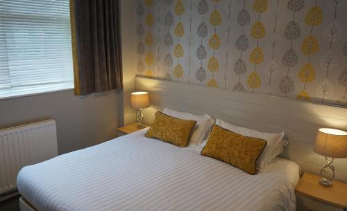 a bedroom with a large white bed with two pillows at Bluebird Lodge in Coniston