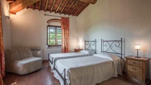 a bedroom with two beds and a chair and a window at Poggio Cennina Resort in Bucine