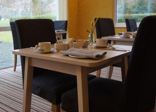 a wooden table with cups and saucers on it at Bluebird Lodge in Coniston