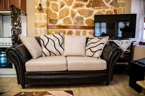 a leather couch in a living room with a tv at The Mouzakles Mansion in Metsovo