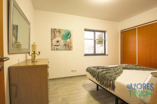 a bedroom with a bed and a dresser and a window at Silver Gate Home in Cinco Ribeiras