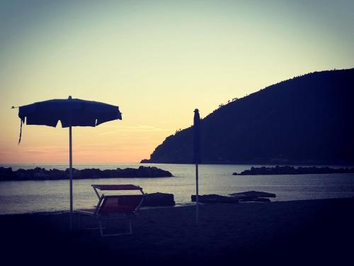 a beach chair and an umbrella on the beach at Casa Anna in Moneglia