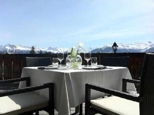 a table with wine glasses and chairs with mountains in the background at Hostellerie du Pas de l'Ours "Relais et Châteaux" in Crans-Montana