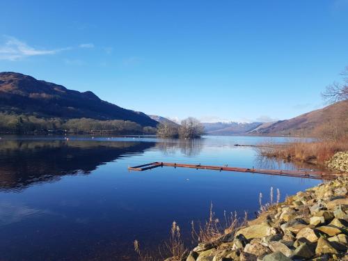 a lake with a dock in the middle of it at Achray House Restaurant with Rooms in Saint Fillans