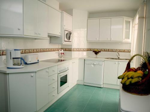 cocina con armarios blancos y suelo verde en Apartamentos Miguel Angel, en Estepona