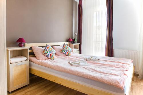 Schlafzimmer mit einem Bett mit rosa Kissen und einem Fenster in der Unterkunft MSE Apartman in Miskolc