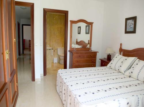 um quarto com uma cama, uma cómoda e um espelho em Apartamentos Miguel Angel em Estepona