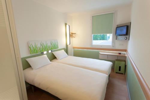 a small room with two beds and a window at ibis budget Cherbourg - La Glacerie in Cherbourg en Cotentin