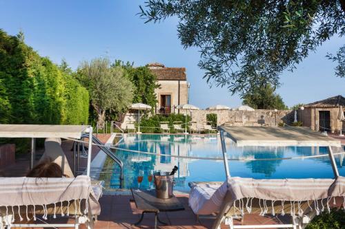 een zwembad met stoelen en een huis bij Hotel Villa Favorita in Noto