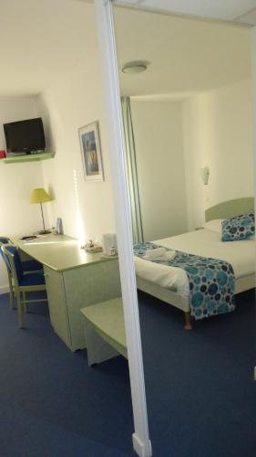 a hotel room with a bed and a desk and a table at Les Balcons Du Velay in Monistrol-sur-Loire