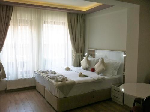 1 dormitorio con 1 cama blanca grande y ventanas en Bayrambey Residence Eskisehir, en Eskisehir