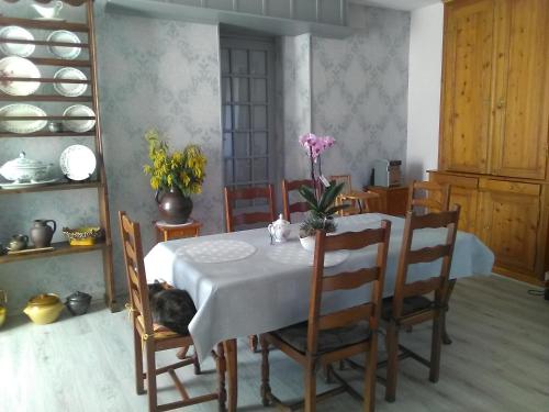 a dining room with a table with a cat laying on it at Chambres d'hôtes les Clématites en Cotentin in Saint-Floxel