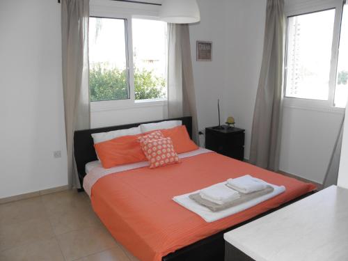 ein Schlafzimmer mit einem Bett mit orangefarbener Bettwäsche und Kissen in der Unterkunft Cosy apartment in a luxury resort in Paralimni