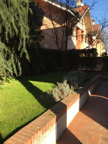a garden with a retaining wall and a lawn at B&B Borgo dei Fiori in Rozzano