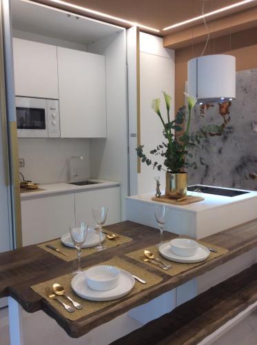a kitchen with a wooden table with plates and glasses at Boulevard Luxury by Sebastiana Group in San Sebastián