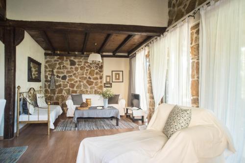 a living room with a white couch and a stone wall at Stone Villas in Nea Roda