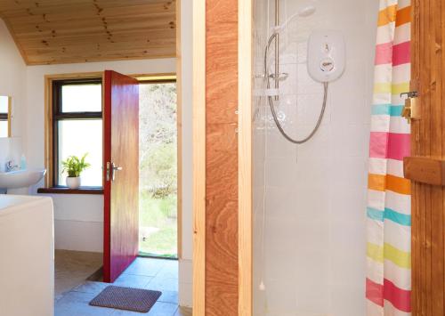 a bathroom with a shower with a rainbow shower curtain at Meadowsweet Forest Lodge in Fintown