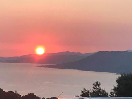 a sunset over a body of water with mountains at Résidence île de beauté in Propriano