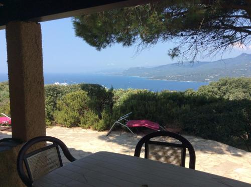 a table and chairs on a porch with a view of the ocean at Résidence île de beauté in Propriano