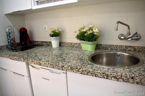 Una encimera de cocina con un fregadero y flores encima. en BENALBEACH DELUXE, en Benalmádena