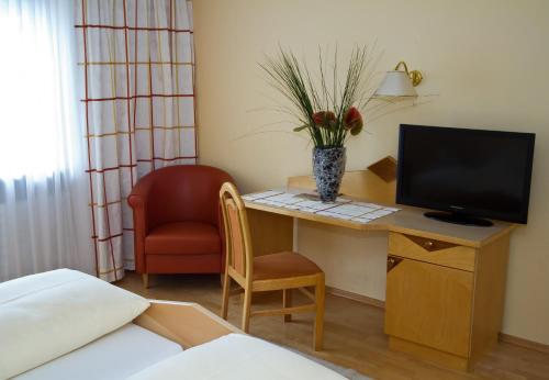 a room with a desk with a television and a chair at Pension Clara in Wattens