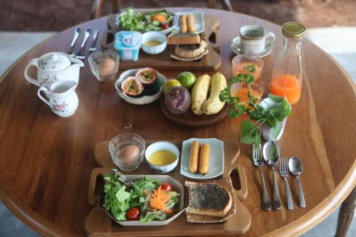 een houten tafel met borden met eten erop bij Mori Natural Farm in Chiang Mai